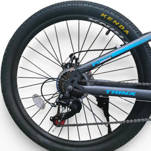 Detailed view of Trinx K024 mountain bike rear drivetrain, Shimano rear derailleur, cassette, chain, and 24-inch Kenda tire