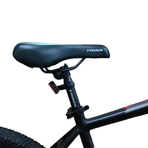 Close-up of Trinx mountain bike saddle and seatpost with integrated rear reflector and white logo.