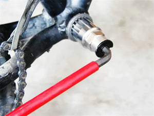 Bicycle bottom bracket removal tool with red wrench in use.
