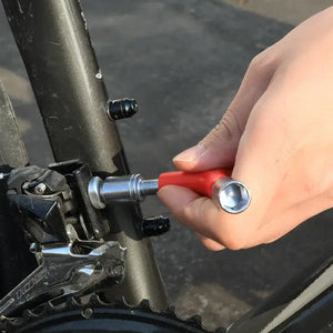 Hand using a red Y-shaped socket wrench on a bicycle front derailleur mounting bolt.