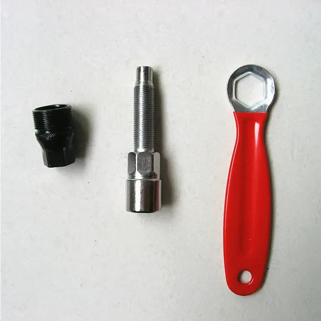 Disassembled bicycle crank puller with a black threaded adapter, silver extractor bolt and red-handled wrench.