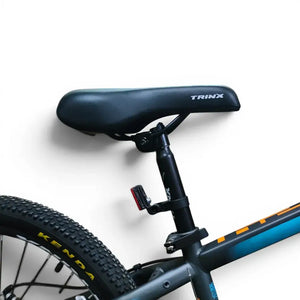 Close-up view of Trinx K024 mountain bike ergonomic saddle, adjustable seatpost with rear safety reflector, and Kenda rear tire