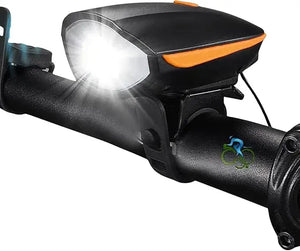 Black bicycle headlight with orange trim and illuminated front LED beam, mounted on a bicycle handlebar.