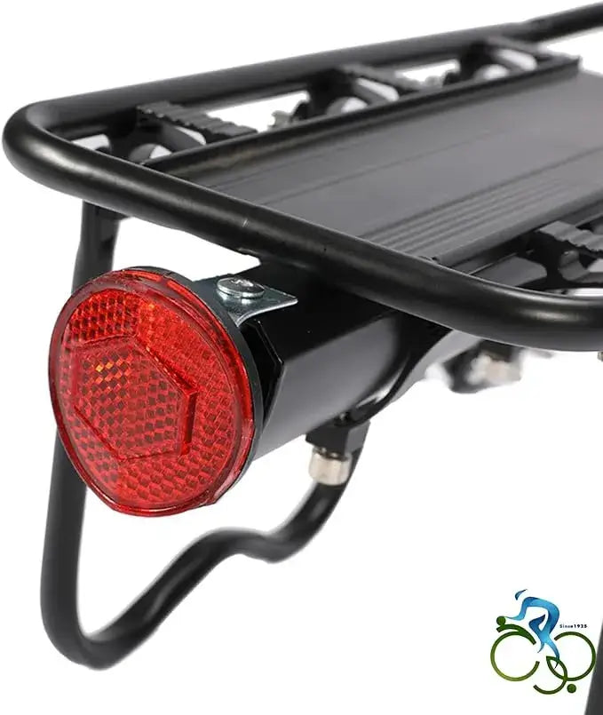 Rear close-up view of a black metal bicycle cargo rack featuring a red hexagonal safety reflector lamp, isolated on white background