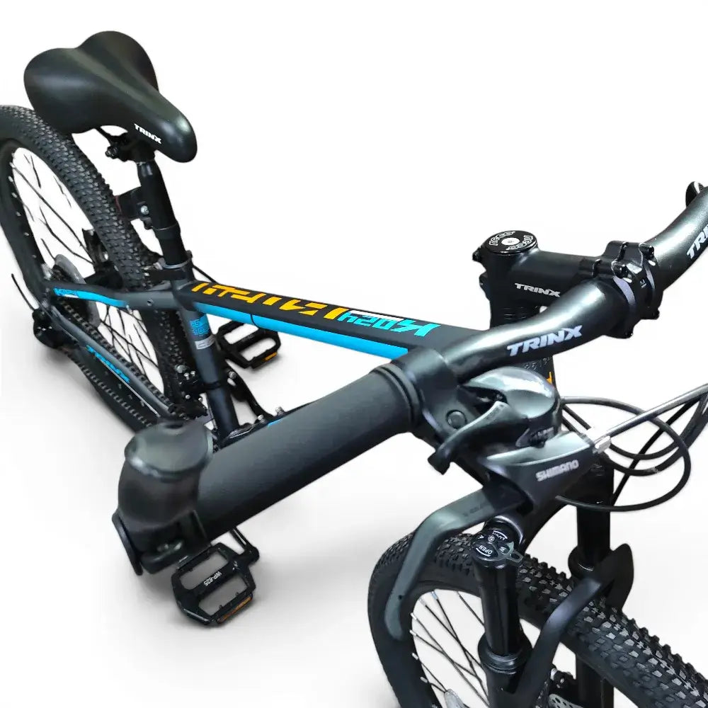 High-angle cockpit view of Trinx K024 mountain bike showing handlebars, Shimano shifters, top tube branding, front suspension, and saddle