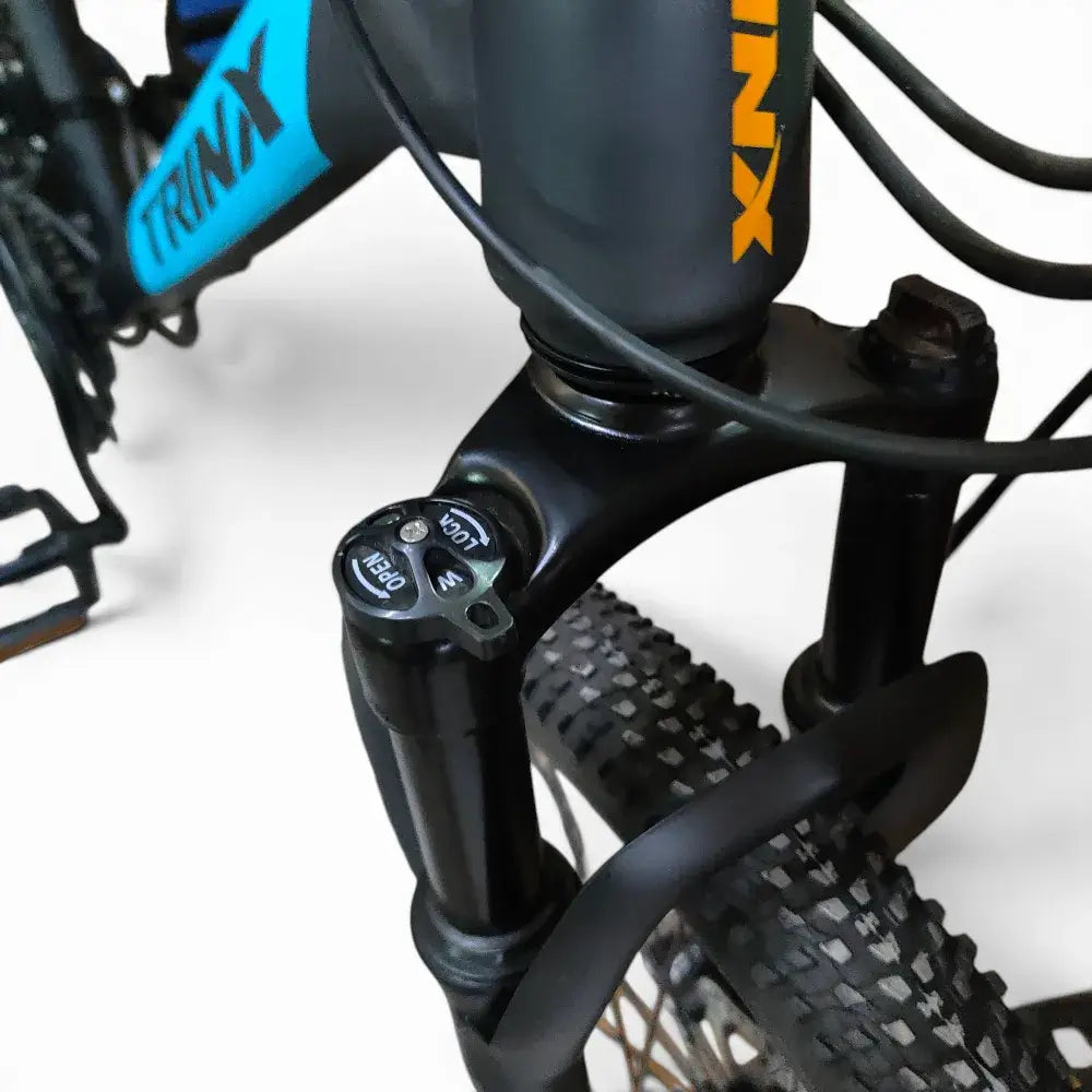 Detailed view of Trinx K024 mountain bike front suspension fork featuring lockout adjustment dial, head tube branding, and front tire