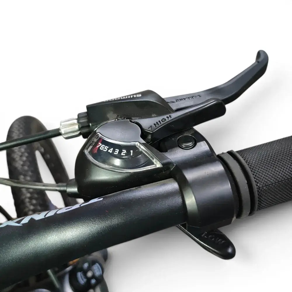 Close-up view of Trinx K024 mountain bike Shimano 7-speed shifter dial, integrated brake lever, and ergonomic handlebar grip