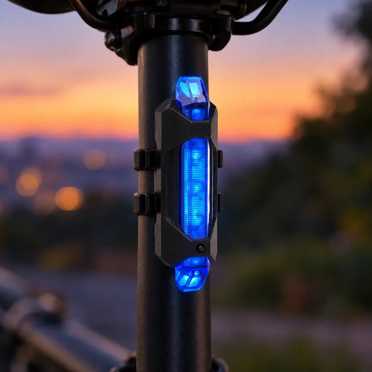Blue bicycle tail light illuminated on a bike seat post at dusk
