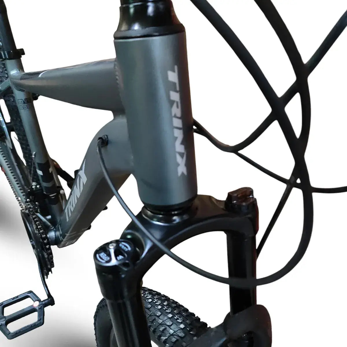 Close-up of Trinx M007 PRO mountain bike frame and front suspension fork, showing dark gray head tube with Trinx logo, brake cables, and front tire.