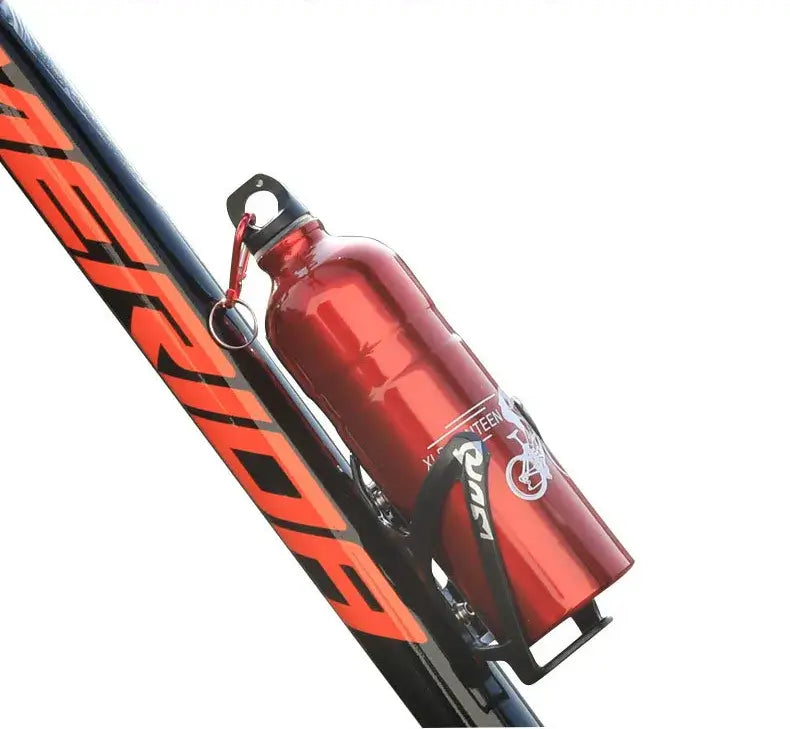 A red insulated water bottle with a black carabiner clip and black bottle strap, mounted on a black and orange bicycle frame against a white background