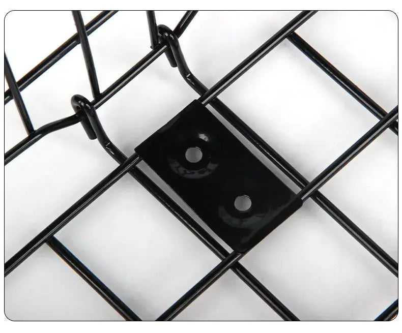 Close-up product photograph focusing on the reinforced metal mounting plate with two screw holes on the black wire grid of a bicycle basket, on a plain white background