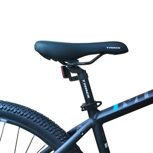 Close-up view of black Trinx bicycle saddle and seatpost mounted on blue-accented frame, isolated on white background