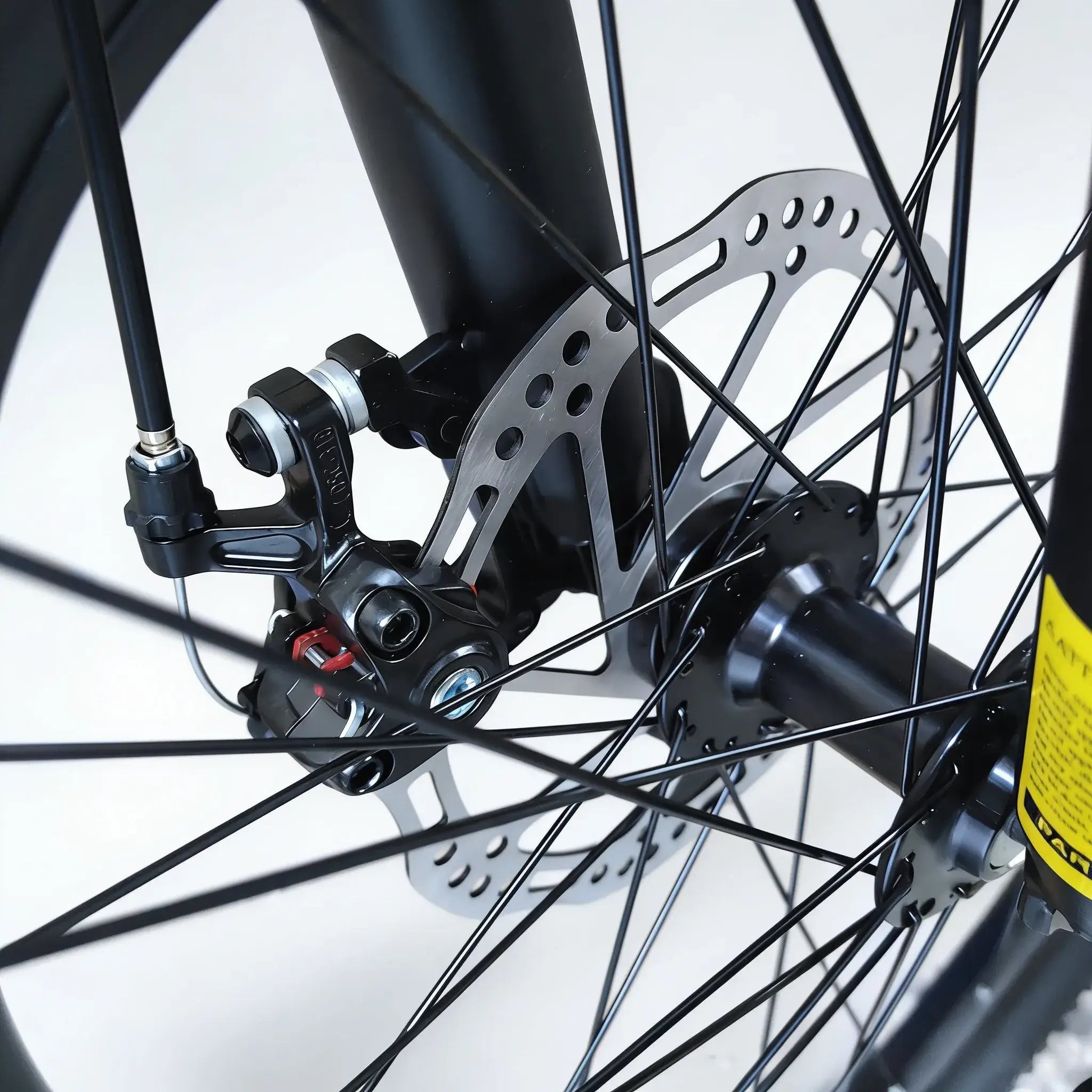 Close-up view of mechanical disc brake assembly and front wheel hub on Trinx mountain bike, isolated on white background